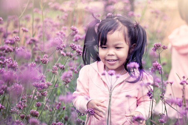 Niño feliz niña corriendo y divirtiéndose en el campo de flor púrpura