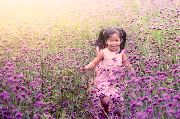 Niño feliz niña corriendo y divirtiéndose en el campo de flor púrpura