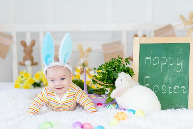 Niño feliz con orejas de conejo en la cabeza acostado con un conejo en la cama con huevos de Pascua lindo bebé sonriente divertido El concepto de Pascua