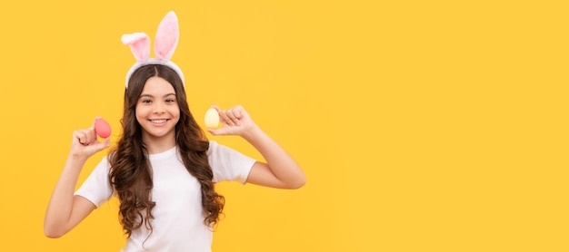 Niño feliz en orejas de conejo sostiene huevos sobre fondo amarillo Cartel horizontal de niño de Pascua Encabezado de banner web de espacio de copia de niño conejito