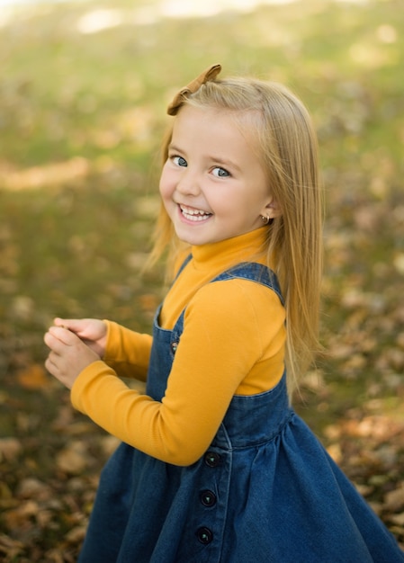 Un niño feliz en un parque de otoño con el telón de fondo de hojas amarillas borrosas