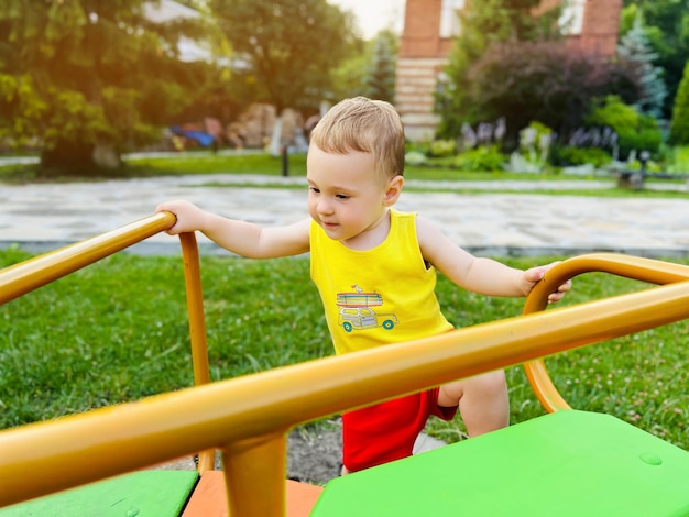 Niño feliz paseos en un columpio Patio interior Un lindo niño de un año y medio Enfoque selectivo