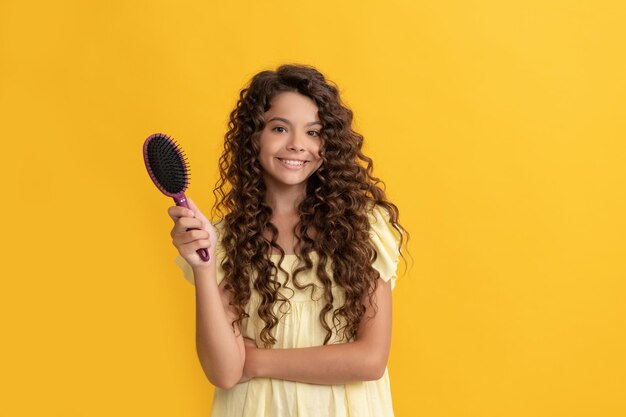 Niño feliz con el pelo largo y rizado con peine cepillo para peinar, belleza