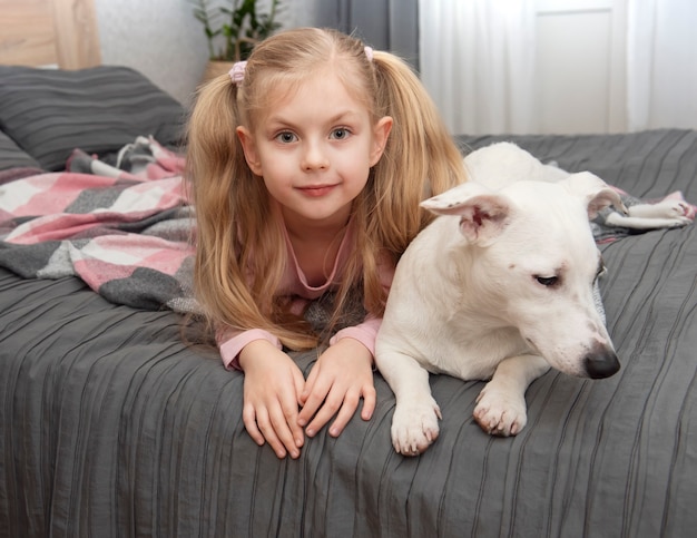 Niño feliz con perro. Retrato de niña con mascota. Chica y Jack Russell blanco