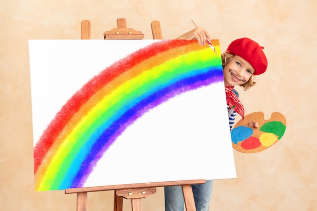 Niño feliz pintando arco iris en casa.