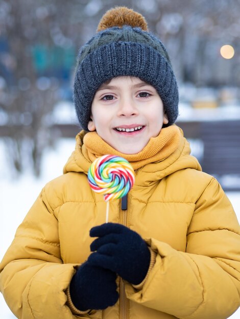 un niño feliz con una piruleta en invierno