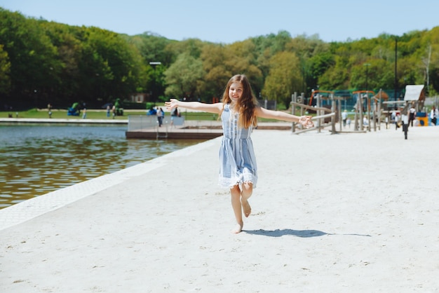 Niño feliz en la playa niña rubia corre a lo largo de la arena en la playa