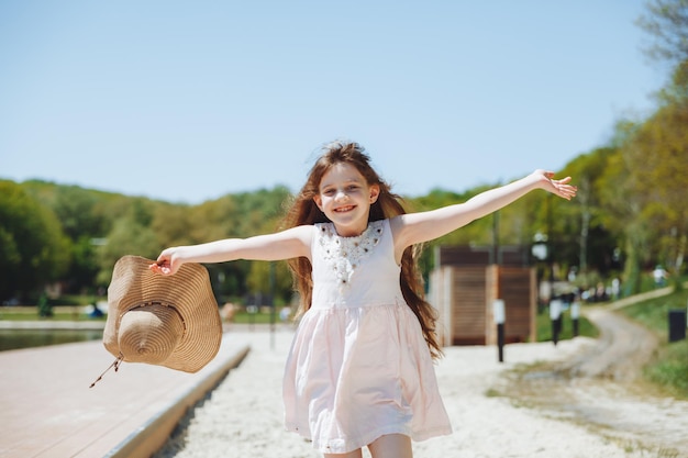 Niño feliz en la playa niña rubia corre a lo largo de la arena en la playa