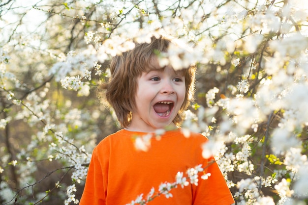 Niño feliz de primavera con árbol floreciente verano parque jardín concepto niño sonriente al aire libre