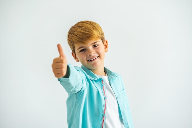 Foto el niño feliz pulgar hacia arriba sobre el fondo blanco.