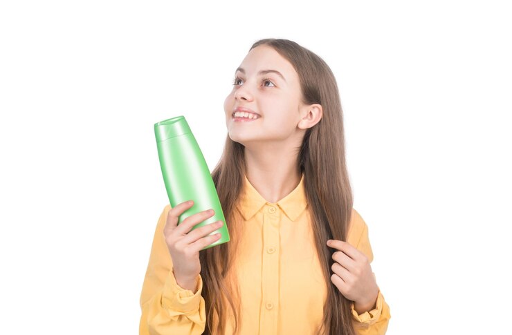 Foto niño feliz que presenta una botella de champú o acondicionador corporal aislado en el cuidado del cabello blanco