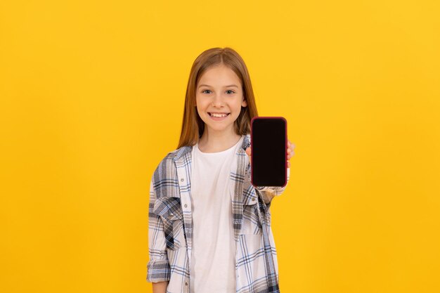 Niño feliz que presenta el producto de la pantalla de demostración del smartphone moderno para el espacio de la copia, publicidad.
