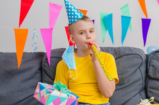 Niño feliz se quitó la mascarilla y soplando en pipa festiva