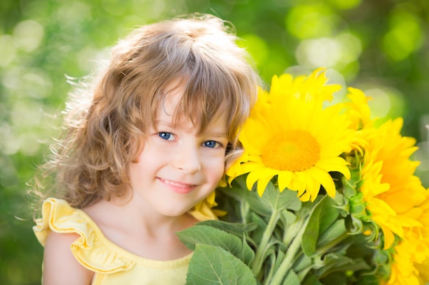 Niño feliz con ramo de flores sobre fondo verde Concepto de vacaciones familiares de primavera Día de la madre