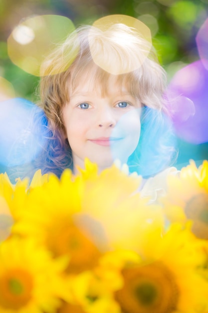 Niño feliz con ramo de hermosos girasoles sobre fondo verde Concepto de vacaciones familiares de primavera Día de la madre