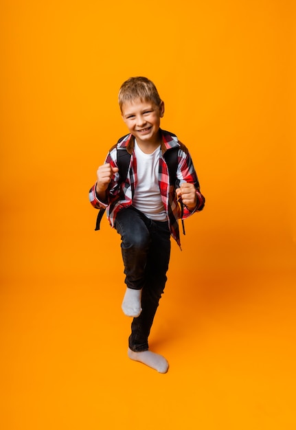 Niño feliz se regocija en la victoria sobre un fondo amarillo. colegial alegre