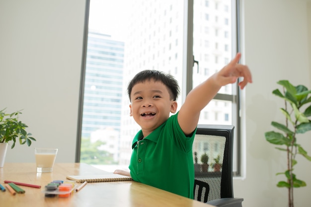 Niño feliz riendo mientras estudia y apunta a la cámara