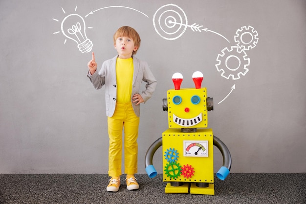 Niño feliz con robot. Niño divertido jugando en casa. Concepto de tecnología de éxito, creatividad e innovación.