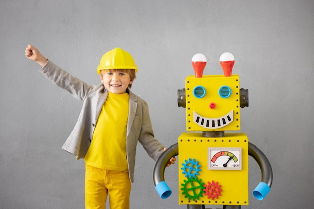 Niño feliz con robot. Niño divertido jugando en casa. Concepto de tecnología de éxito, creatividad e innovación.