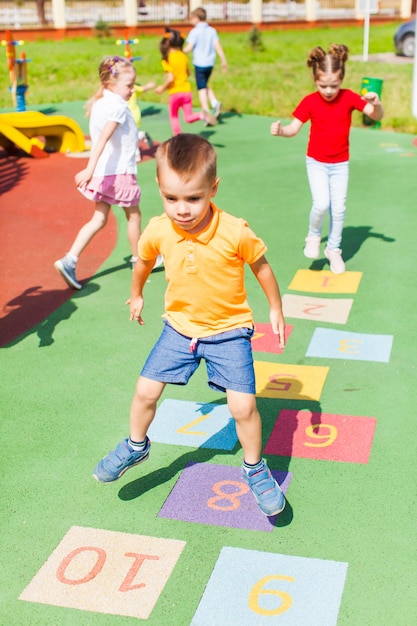 Niño feliz salta jugando a la rayuela en la escuela