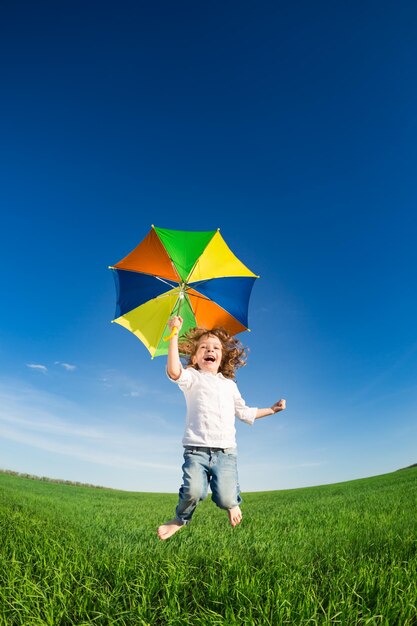 Niño feliz saltando en campo verde contra el cielo azul Concepto de vacaciones de verano