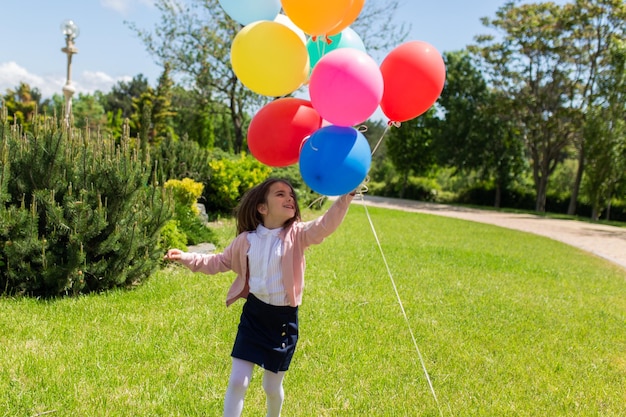 Niño feliz saltando con coloridos globos de juguete al aire libre