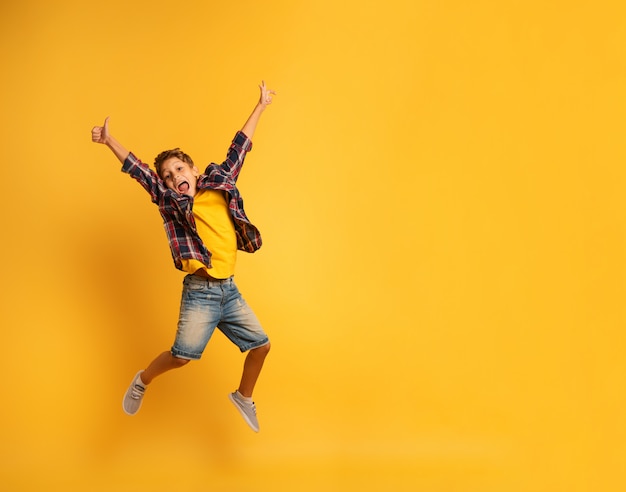 Niño feliz saltando sobre un fondo amarillo