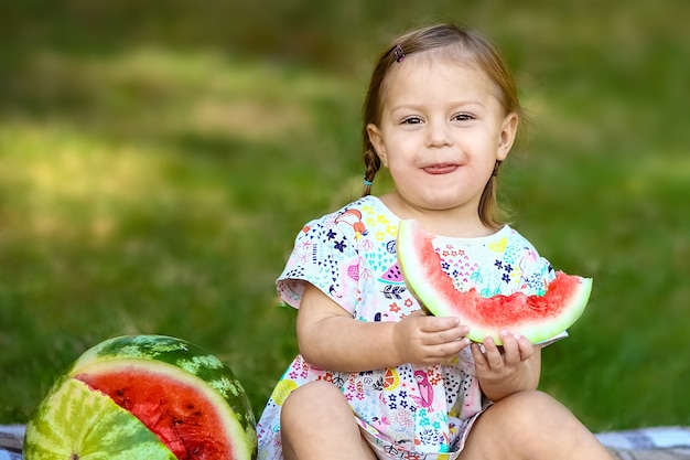 Niño feliz con sandía en la naturaleza en el parque