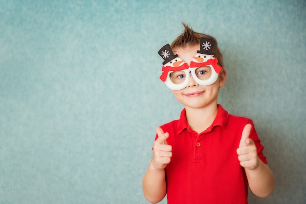 Niño feliz de santa usa gafas de fantasía. Traje festivo, accesorios de vacaciones. Navidad y Año Nuevo