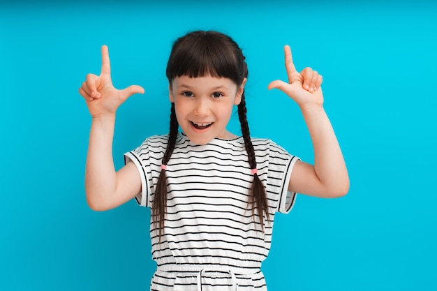 Niño feliz señalando con el dedo en la parte superior Los puntos de la niña muestran un espacio vacío para copiar