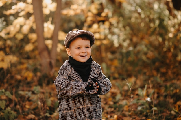 Un niño feliz sincero con un abrigo de otoño camina en un parque amarillo de otoño.