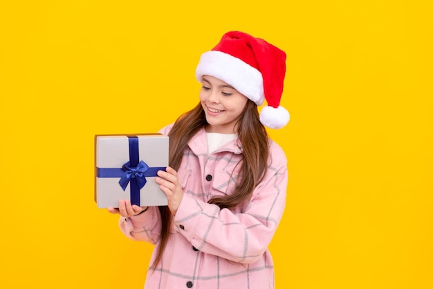 Niño feliz con sombrero de santa claus chica adolescente con regalo sobre fondo amarillo regalo de vacaciones de navidad