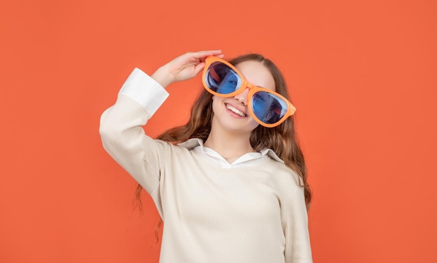 Niño feliz sonriendo en grandes gafas divertidas fondo marrón