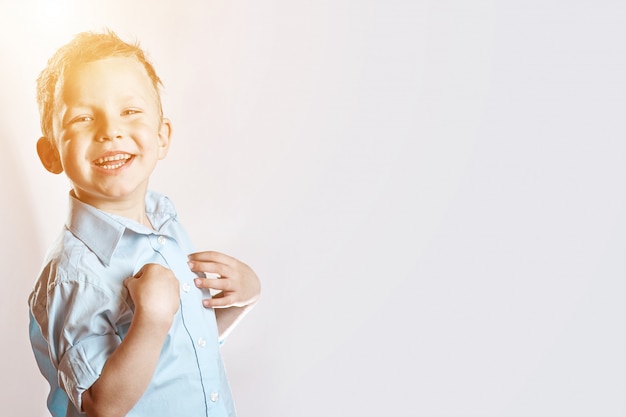 Un niño feliz sonriente en camisa azul en luz