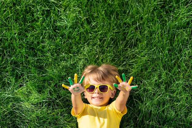 Niño feliz con una sonrisa en las manos al aire libre. Cabrito en la hierba verde de primavera. Concepto de ecología y estilo de vida saludable