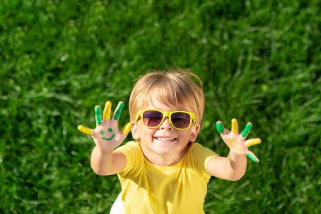 Niño feliz con una sonrisa en las manos al aire libre Niño en hierba verde primavera Ecología y concepto de estilo de vida saludable