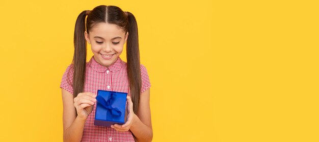 Niño feliz sostenga la caja de regalo sobre fondo amarillo presente Niño con cartel horizontal de regalo de cumpleaños Encabezado de banner con espacio de copia