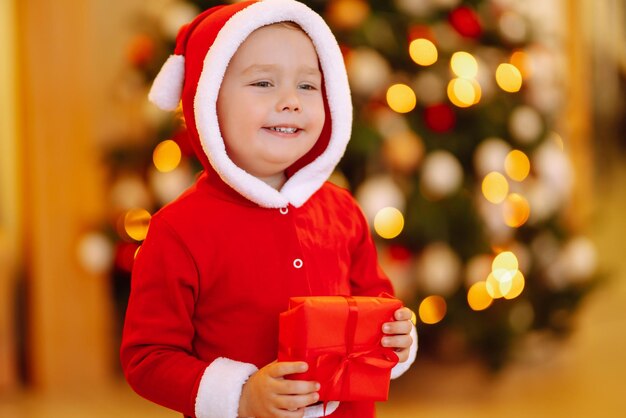 Niño feliz sosteniendo una caja de regalo roja en las luces de fondo