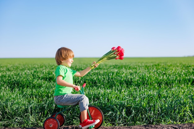 Niño feliz sosteniendo flores contra el fondo de cielo azul