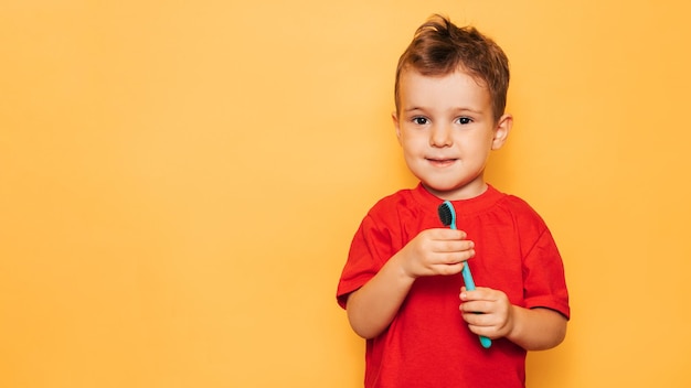 El niño feliz sostiene un cepillo de dientes sobre un fondo amarillo y sonríe mostrando sus dientes Cuidado de la salud higiene bucal Un lugar para su texto