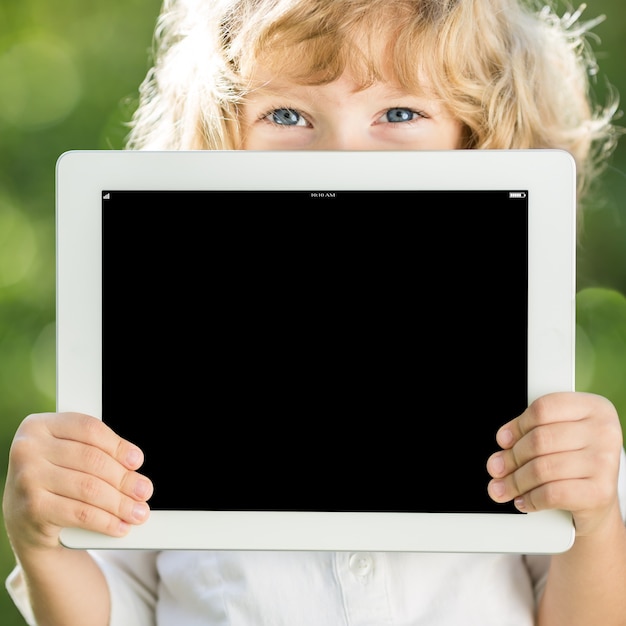 Niño feliz con tablet PC al aire libre en el parque de la primavera