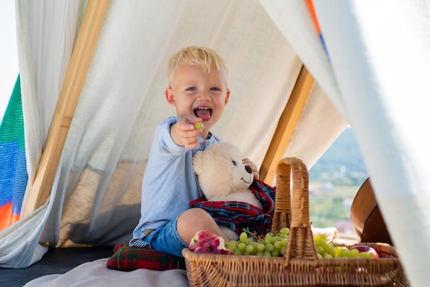 Niño feliz en tienda Niño jugando en tienda Niños acampando Divirtiéndose al aire libre Camping Cara graciosa de cerca