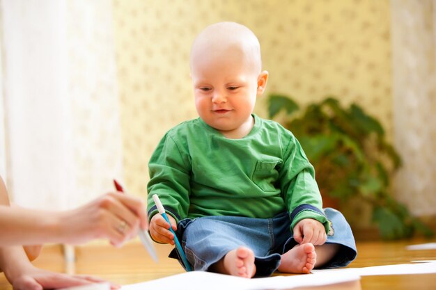 Niño feliz tiene rotuladores en la mano y dibuja. Foto de bebé con fondo borroso