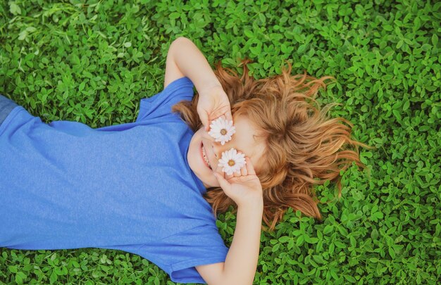 Niño feliz tirado en la hierba verde al aire libre en el parque de primavera