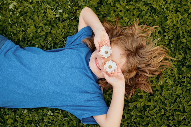 Niño feliz tirado en la hierba verde al aire libre en el parque de primavera