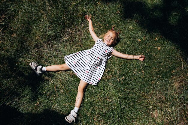 Niño feliz tirado en la hierba verde en el parque Vista superior Vacaciones de verano Copyspace
