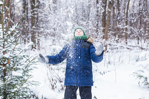 Niño feliz tirando nieve. Concepto de niño, temporada e invierno.