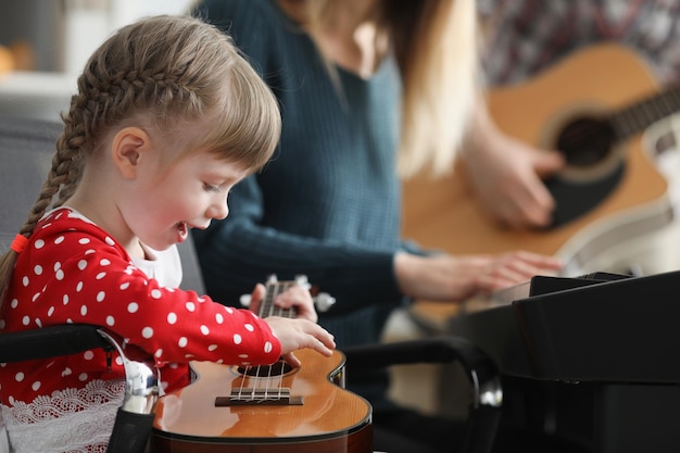 Niño feliz tocando la guitarra aprende una nueva canción en un instrumento musical