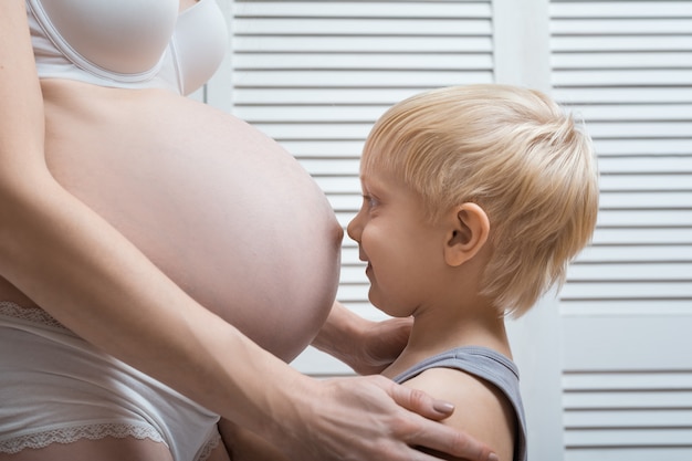 Niño feliz tocando el vientre de la madre embarazada. Joven madre embarazada y su hijo