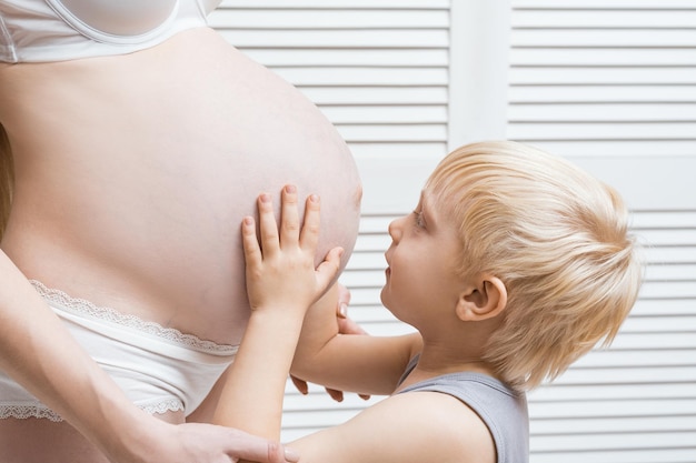 Niño feliz tocando el vientre de la madre embarazada Joven mujer embarazada y su hijo mayor